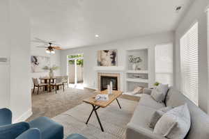 Carpeted living room with recessed lighting, a tile fireplace, and a ceiling fan