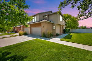View of front facade featuring a garage, driveway, and stucco siding
