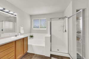 Bathroom with vanity, a stall shower, a garden tub, and wood finished floors
