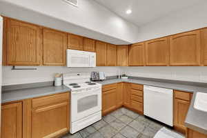 Kitchen featuring white appliances, light tile patterned flooring, recessed lighting, and light countertops