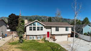 Raised ranch with brick siding, a mountain view, driveway, a garage, and a chimney