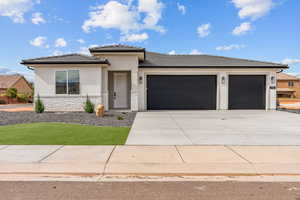 Prairie-style home with a garage, stucco siding, concrete driveway, stone siding, and a tile roof
