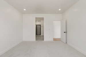 Unfurnished bedroom with light colored carpet and recessed lighting