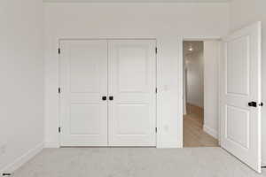 Unfurnished bedroom featuring light carpet and a closet