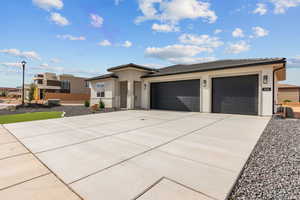 Prairie-style home with stucco siding, a tile roof, driveway, and a garage