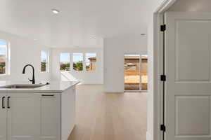 Kitchen featuring light wood-style floors, light stone counters, white cabinetry, and recessed lighting