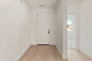 Corridor with light wood-type flooring and baseboards
