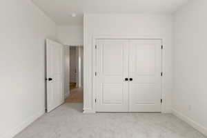 Unfurnished bedroom featuring light colored carpet and a closet