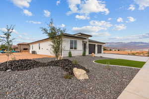 View of front of home featuring stucco siding, a mountain view, concrete driveway, brick siding, and an attached garage
