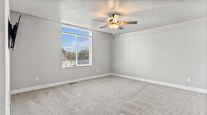 Carpeted spare room with a textured ceiling and ceiling fan