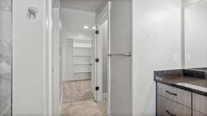 Bathroom with vanity, a walk in closet, and recessed lighting