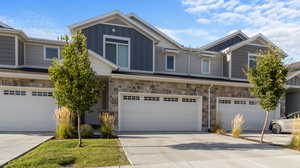 Craftsman-style house with board and batten siding, stone siding, concrete driveway, and a garage
