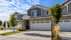 Craftsman-style home with stone siding, a garage, board and batten siding, and driveway