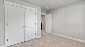 Unfurnished bedroom with light carpet and a closet