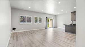 Unfurnished living room with a textured ceiling, light wood-type flooring, and recessed lighting