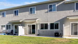 Back of house with a patio area, a lawn, and stucco siding