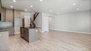 Kitchen with a textured ceiling, light brown cabinetry, recessed lighting, light wood finished floors, and appliances with stainless steel finishes