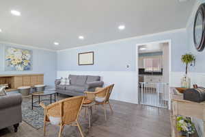 Living room with wainscoting, crown molding, wood finished floors, and recessed lighting
