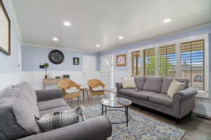 Living room with wood finished floors, crown molding, and recessed lighting