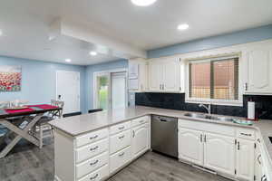 Kitchen with decorative backsplash, a peninsula, stainless steel dishwasher, wood finished floors, and recessed lighting