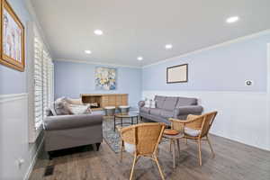 Living room with wainscoting, wood finished floors, crown molding, and recessed lighting