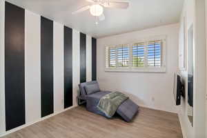 Sitting room featuring light wood-type flooring and a ceiling fan