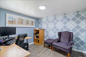 Home office with an accent wall, wallpapered walls, and light wood finished floors