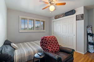 Bedroom with wood finished floors, a closet, and ceiling fan