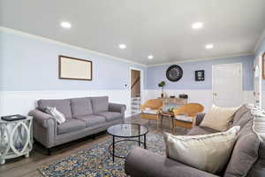 Living room featuring wainscoting, ornamental molding, wood finished floors, recessed lighting, and stairway