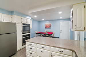 Kitchen featuring stainless steel appliances, light wood finished floors, recessed lighting, white cabinetry, and a peninsula