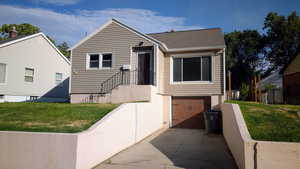 Bungalow featuring a garage, a front lawn, driveway, and a shingled roof