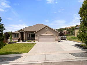 View of front facade with concrete driveway, stucco siding, a front lawn, an attached garage, and a shingled roof