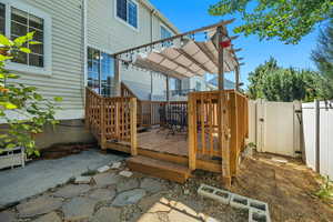 Deck with a fenced backyard, a pergola, and a gate