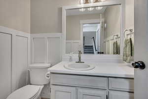Half bath with a decorative wall, a wainscoted wall, and vanity
