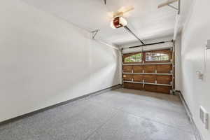 Garage featuring baseboards and a garage door opener