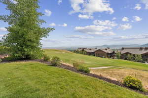View of green lawn featuring a mountain view and view of golf course