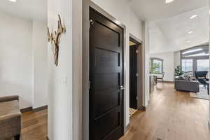 Hallway with recessed lighting, wood-type flooring, and lofted ceiling
