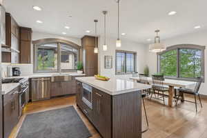 Kitchen featuring appliances with stainless steel finishes, a center island, backsplash, light countertops, and light wood-type flooring