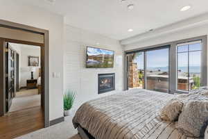 Bedroom featuring access to exterior, light carpet, a tile fireplace, a textured ceiling, and recessed lighting