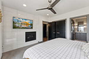 Bedroom with recessed lighting, a glass covered fireplace, carpet floors, ensuite bath, and a ceiling fan
