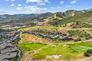 Aerial view of property's location featuring a mountain backdrop, a golf club, and nearby suburban area