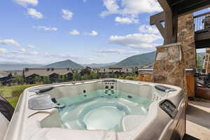 View of patio with a mountain view and a hot tub