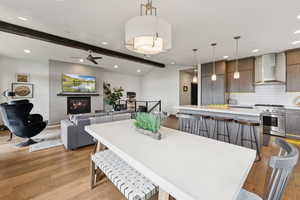 Dining room with light wood-style floors, recessed lighting, a ceiling fan, and a glass covered fireplace