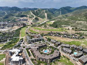 Aerial view of property and surrounding area featuring a golf club and a mountainous background