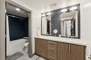 Bathroom featuring a textured ceiling, double vanity, tile patterned floors, and shower / bath combination with curtain