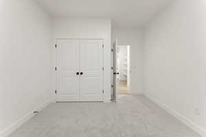 Unfurnished bedroom featuring light colored carpet and a closet
