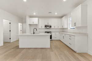 Kitchen featuring white cabinets, stainless steel appliances, light wood-style flooring, and recessed lighting