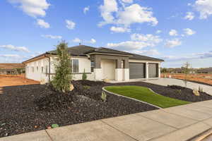 Prairie-style home with brick siding, concrete driveway, stucco siding, and an attached garage