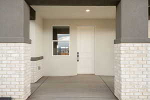 Doorway to property featuring stucco siding and a patio