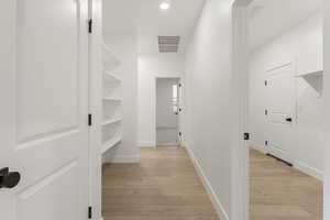 Corridor with light wood-type flooring and recessed lighting
